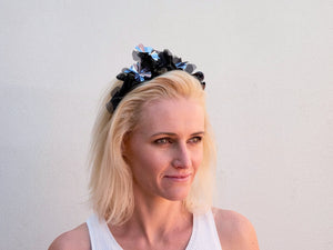 Blonde model wearing Sylvie headband in black metallic flowers. Handmade Millinery made in London.