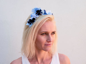 Blonde model wearing Sylvie headband in blue, white and navy metallic flowers. Handmade Millinery made in London.
