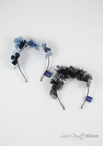 Two Sylvie metallic headbands, one blue and one black. Top view.